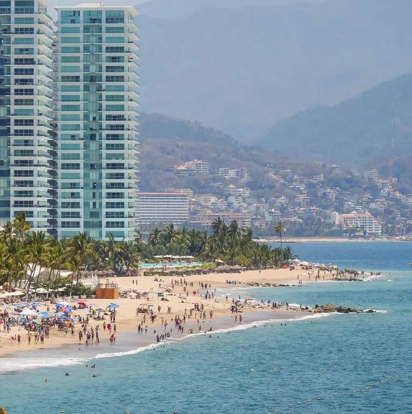 busy beach with tourists and condos puerto vallarta