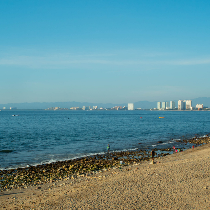 A Bright Blue Beach at Noon with Buildings in the Distance in Puerto Vallarta Mexico