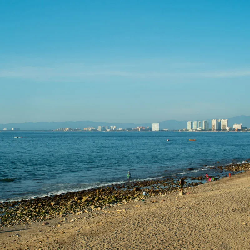 A Bright Blue Beach at Noon with Buildings in the Distance in Puerto Vallarta Mexico