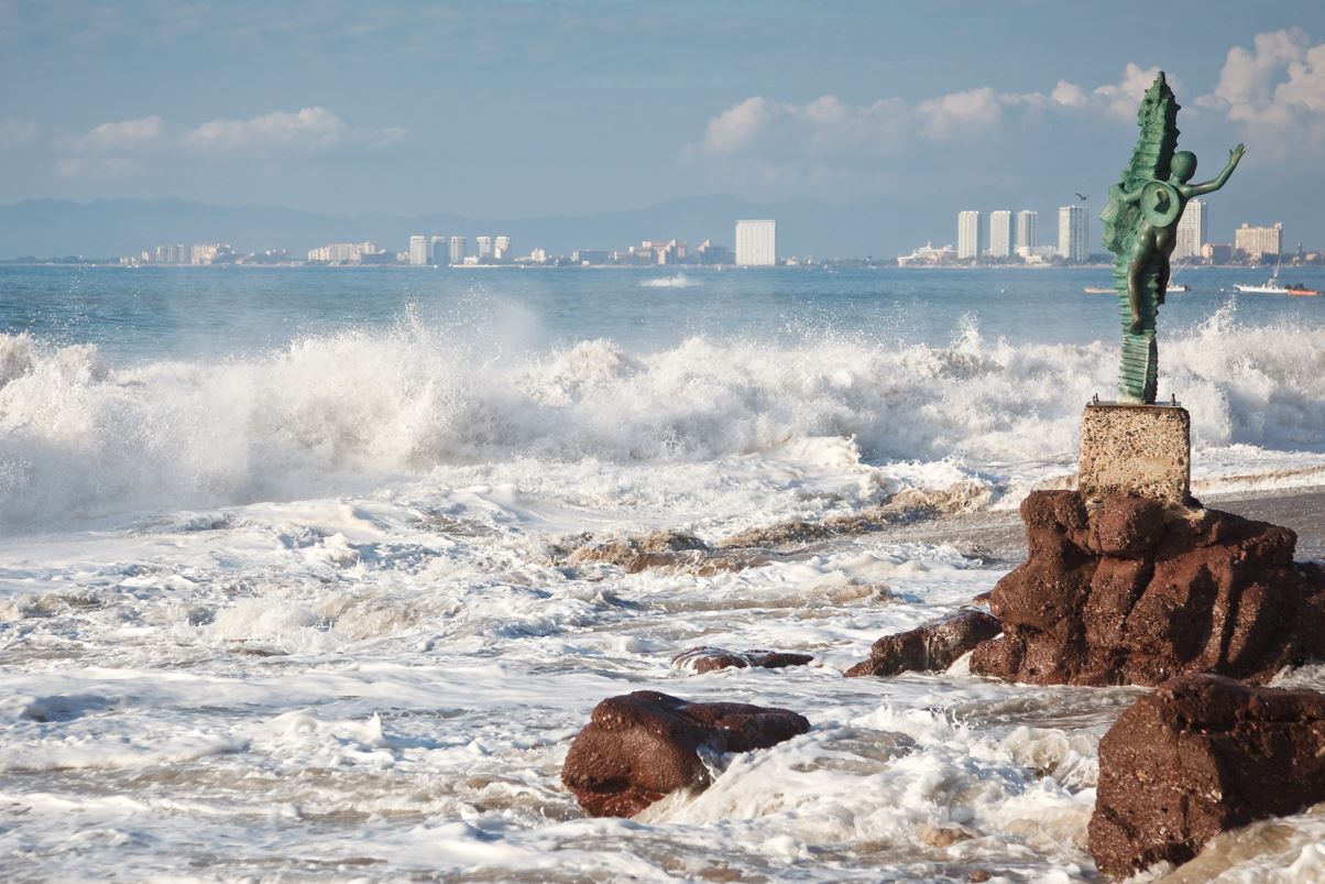 waves crashing on beach with statue puerto vallarta