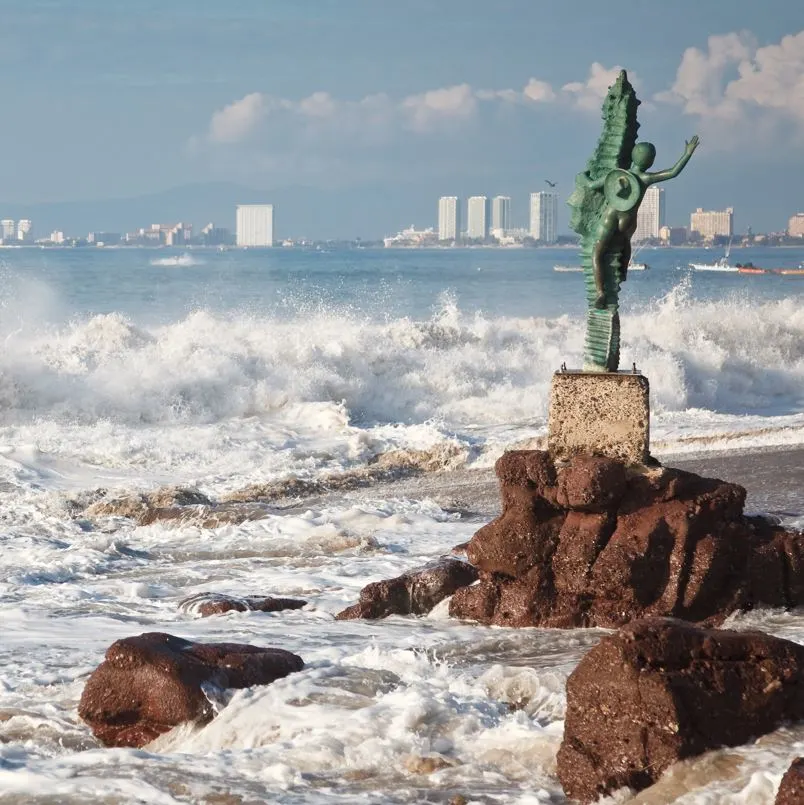 waves crashing on beach with statue puerto vallarta
