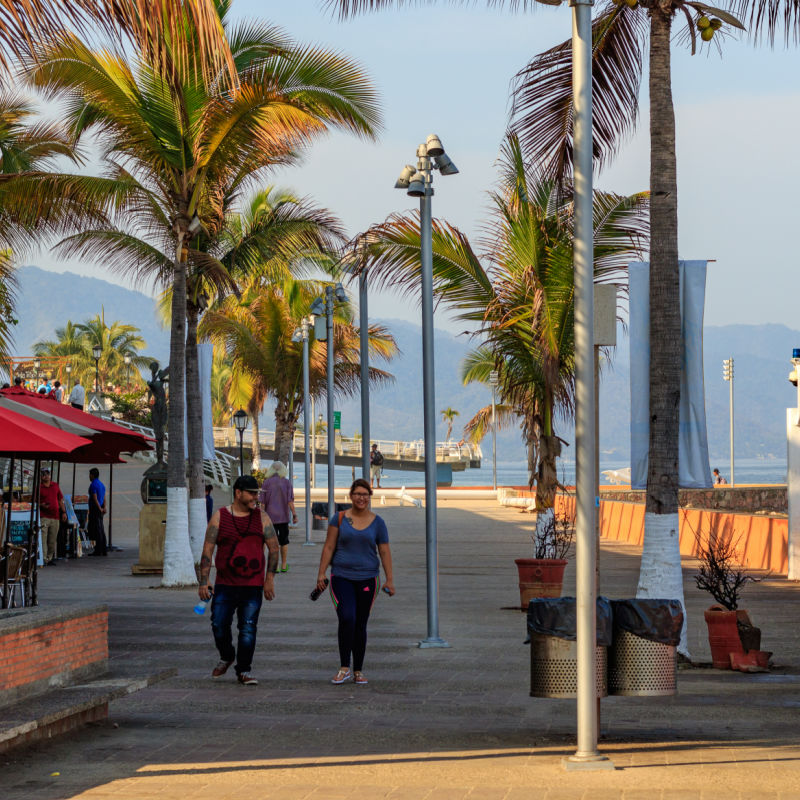 Puerto Vallarta Mexico. People walking on the malecón with view of mountains and Banderas Bay.