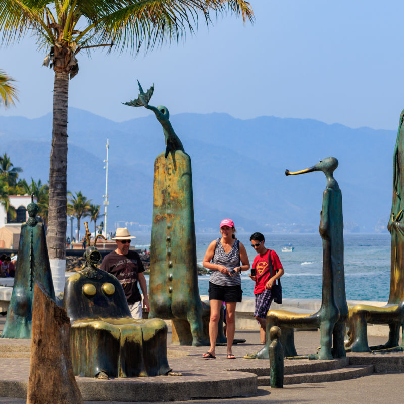 Tourists on the malecón with mountains and Banderas Bay in the background in Puerto Vallarta